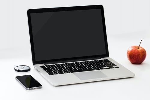 laptop, smart phone, and apple on a white desk