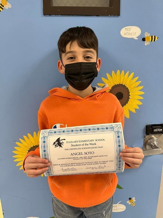 student holding an award certificate in the school hallway